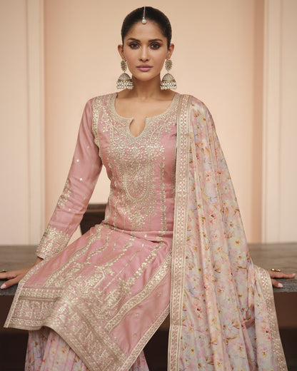 Woman wearing a traditional pink embroidered outfit with a matching dupatta against a beige background