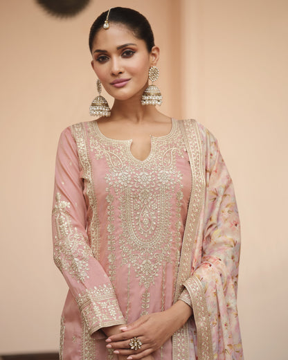 Woman wearing a traditional pink and gold embroidered outfit with a plain background