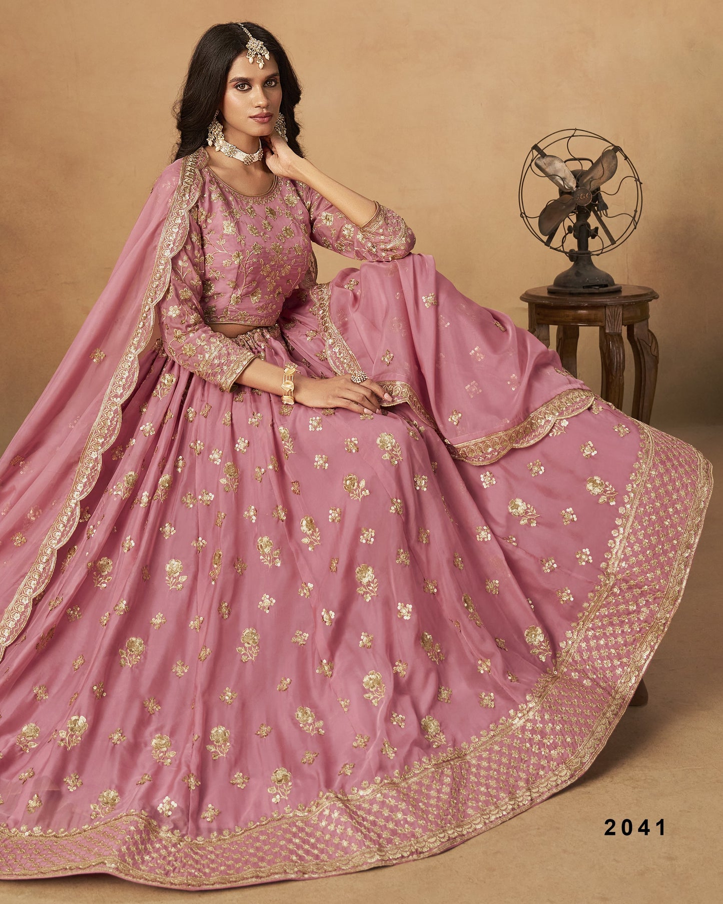 Woman in a pink traditional outfit with gold embroidery on a beige background