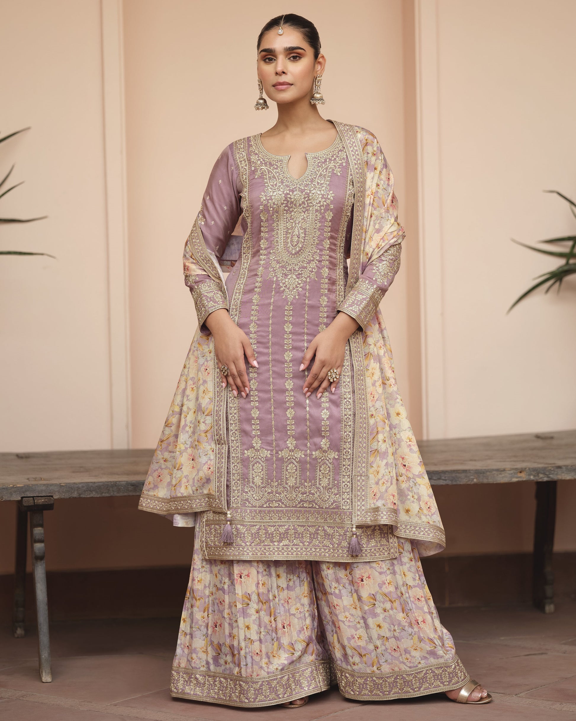 Woman wearing a traditional outfit with intricate patterns on a neutral background