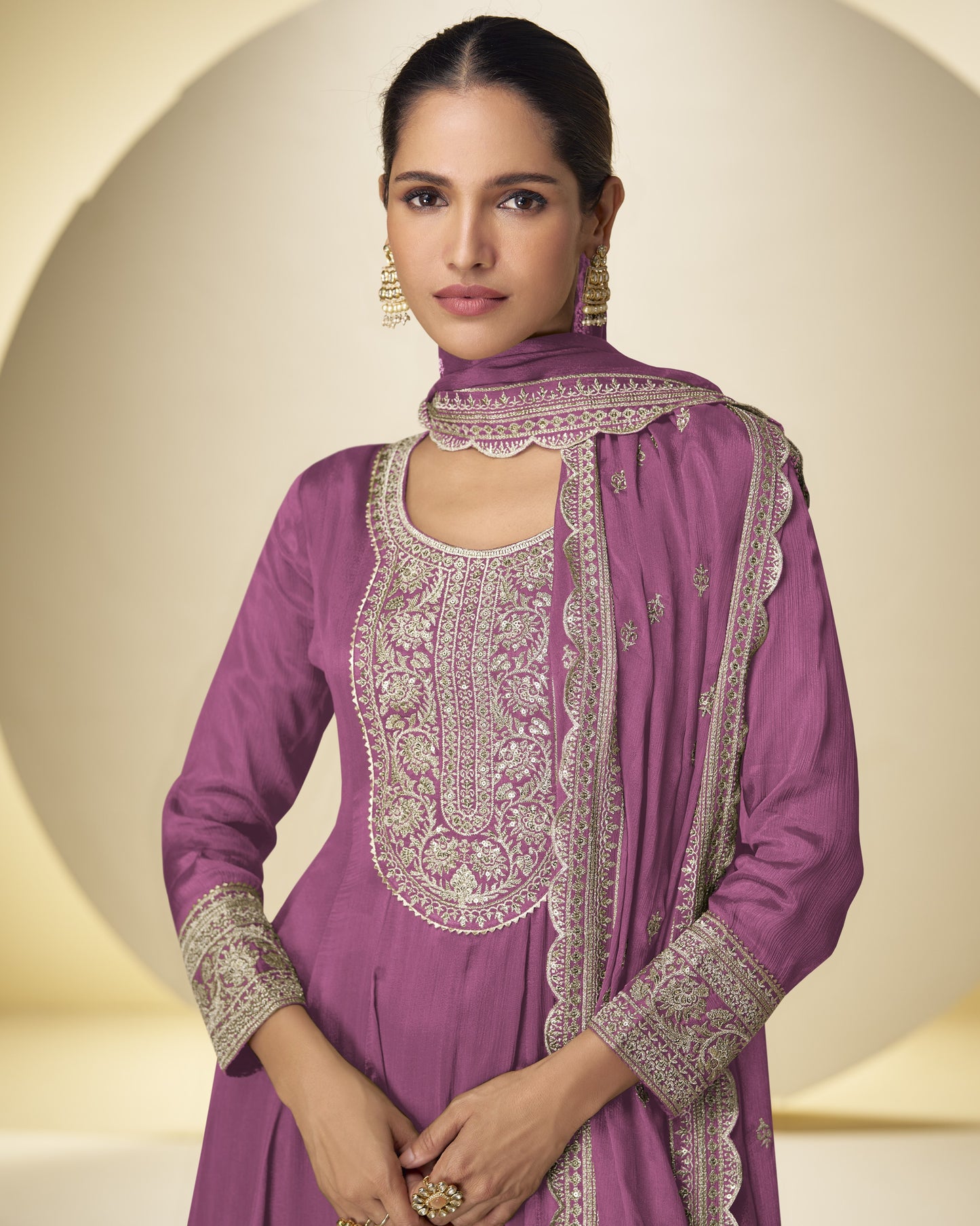 Woman wearing a purple embroidered traditional outfit with a matching dupatta against a neutral background
