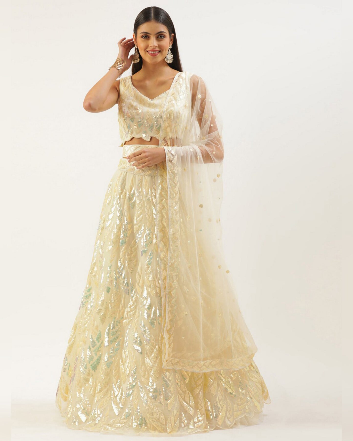 Woman wearing a beige embroidered lehenga with a matching dupatta on a white background