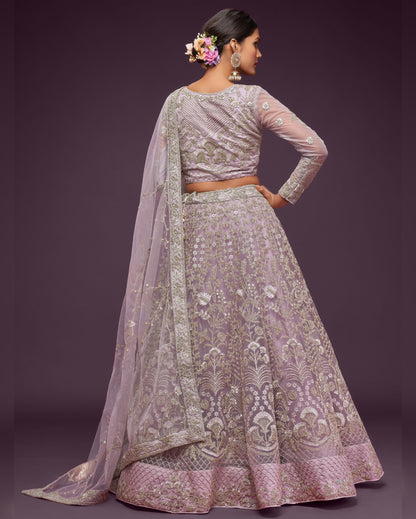 Woman wearing a traditional embroidered outfit with a sheer dupatta against a dark background