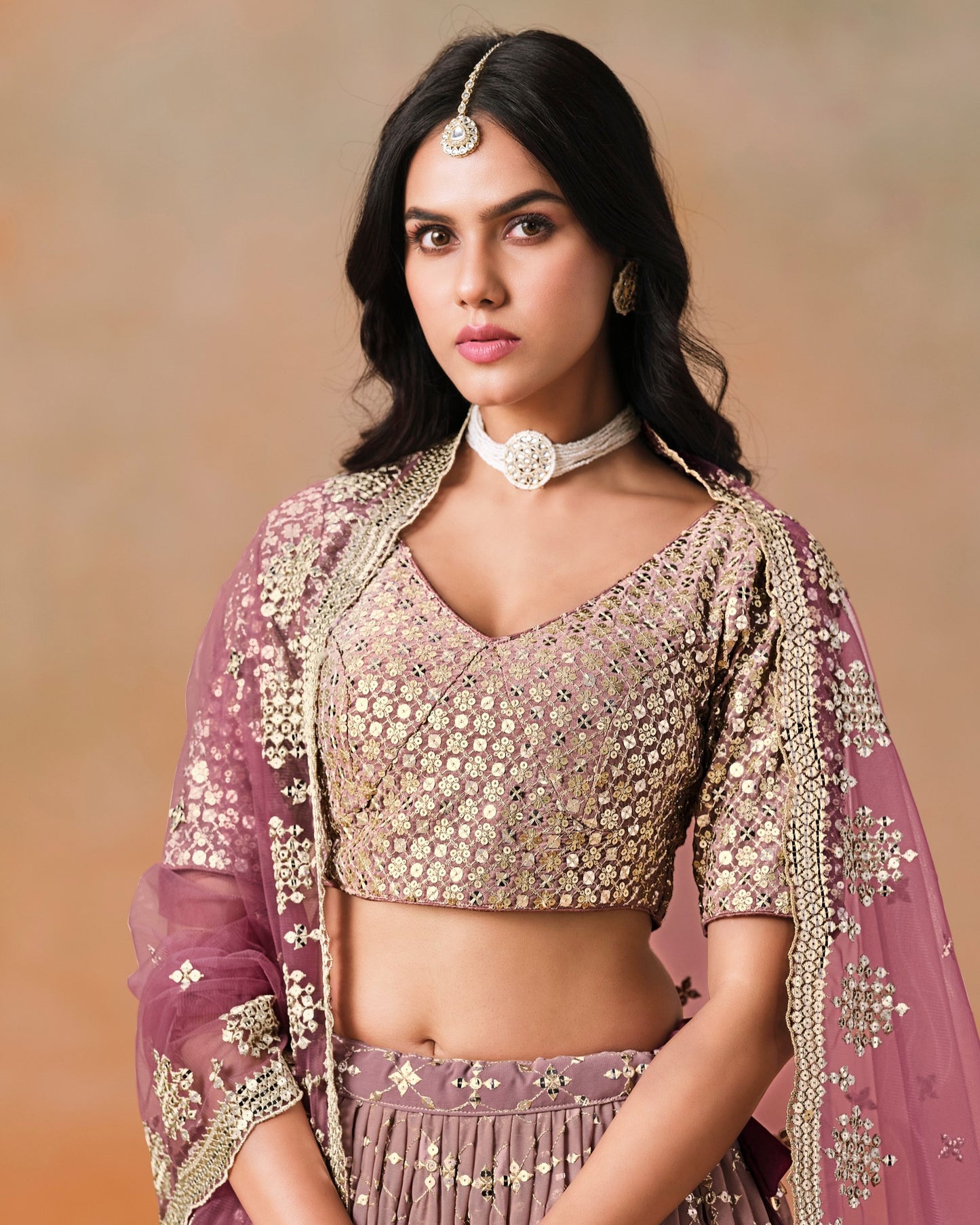 Woman wearing a traditional outfit with intricate designs on a beige background