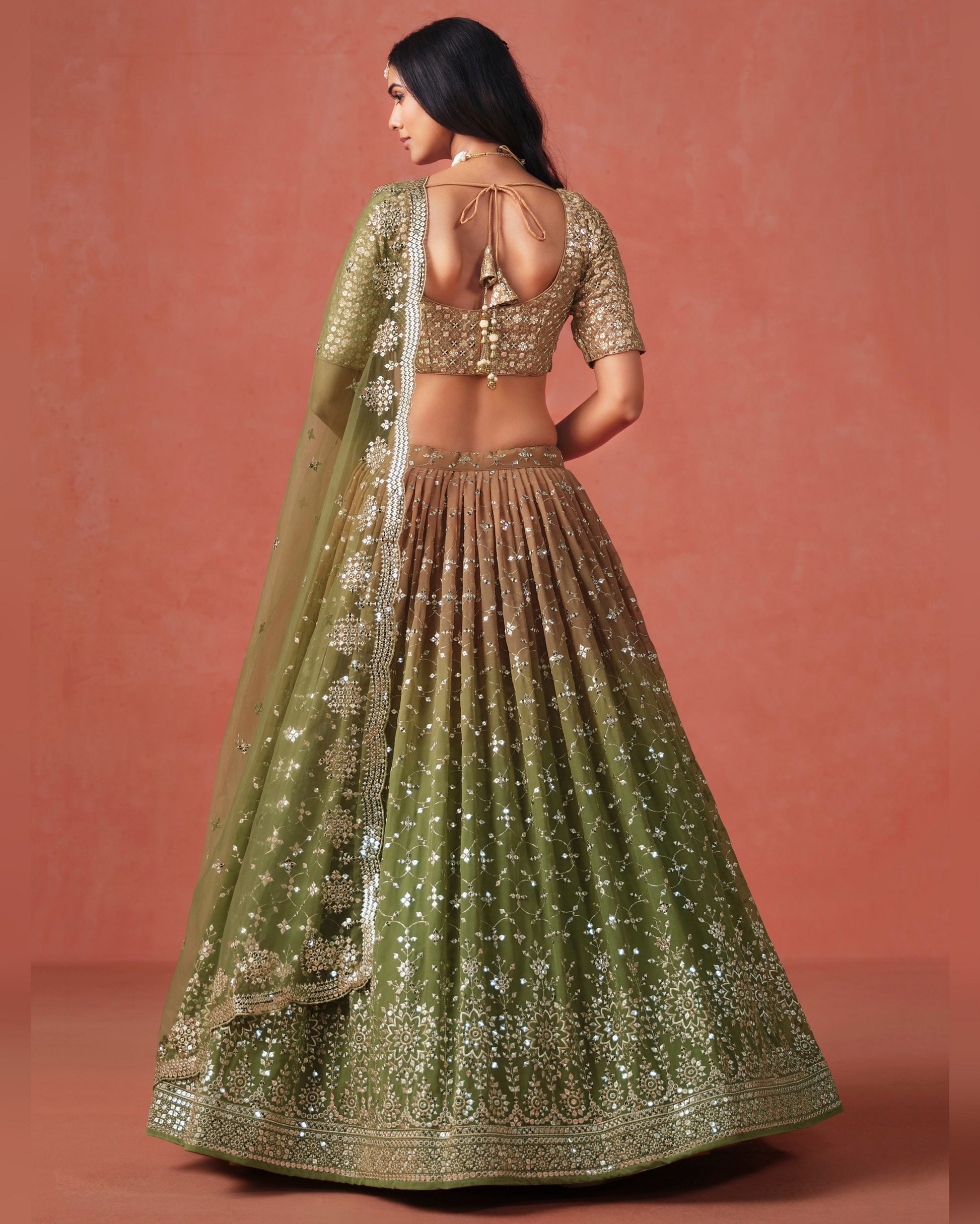 Woman wearing a green and gold traditional outfit with a plain background