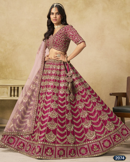 Woman wearing a traditional pink and red embroidered lehenga with a beige background