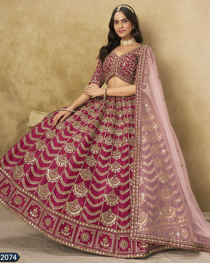 Woman wearing a traditional pink and gold embroidered lehenga with a beige background