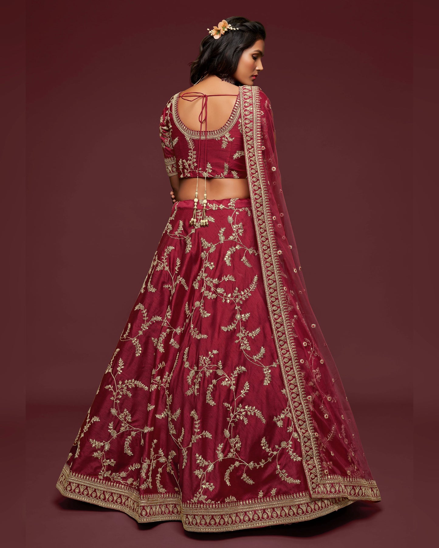 Maroon embroidered traditional outfit with gold details on a dark red background