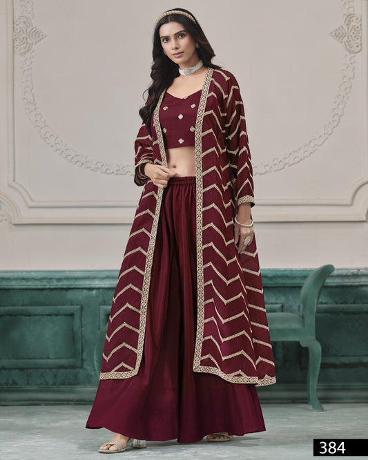 Woman wearing a maroon traditional outfit with gold patterns in an elegant room.