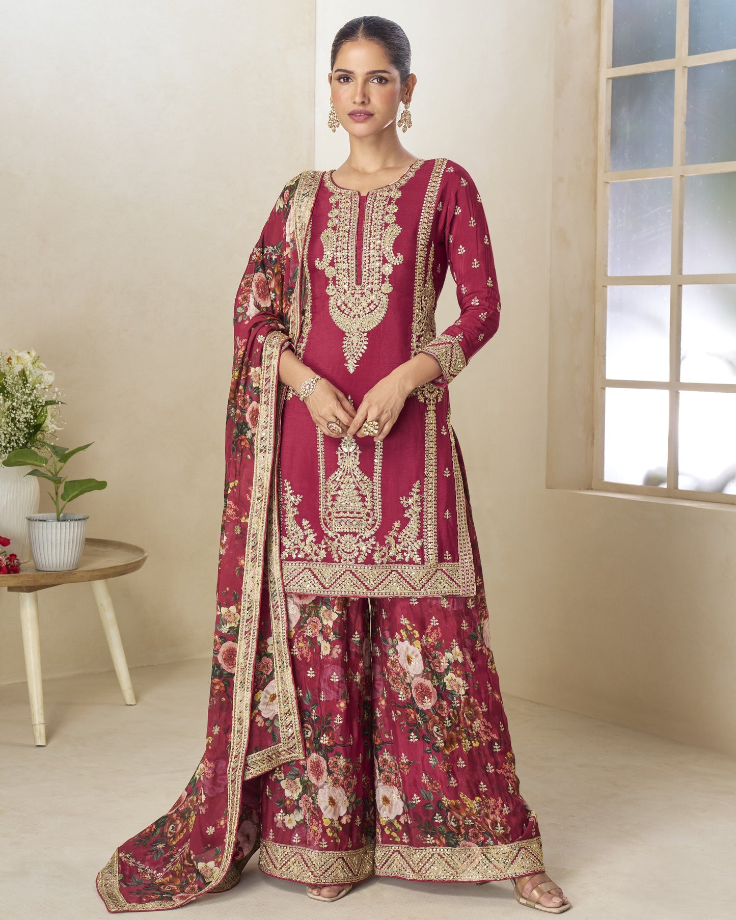 Woman wearing a traditional maroon embroidered outfit with a floral dupatta in a well-lit room.