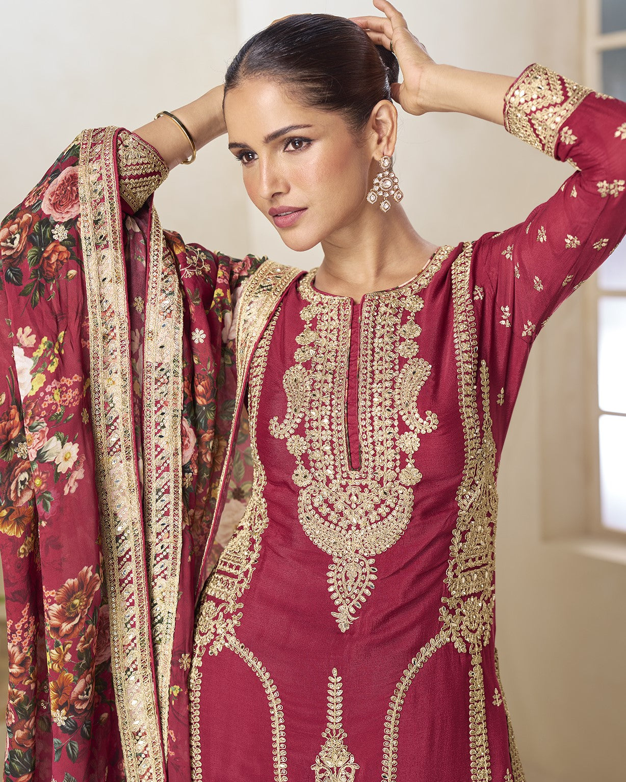 Woman wearing a maroon embroidered traditional outfit with a floral dupatta.