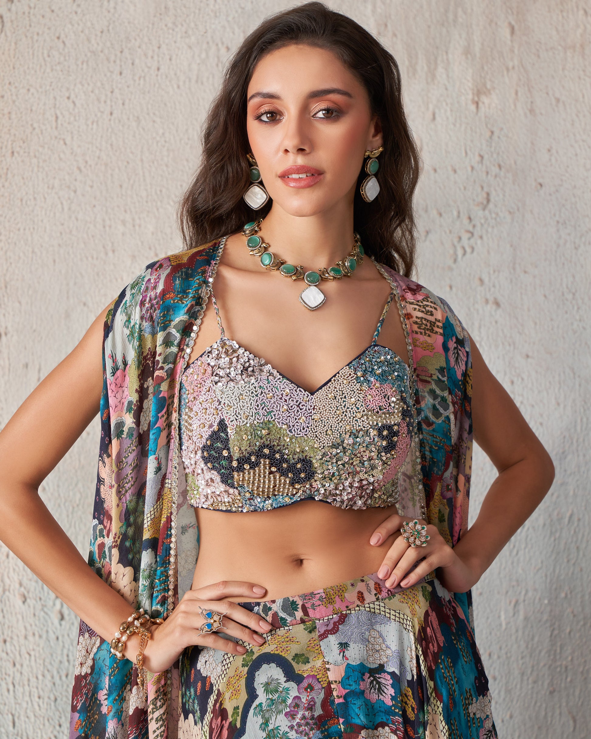 Woman wearing a colorful outfit with a patterned top and skirt against a neutral background