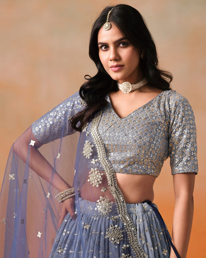 Woman wearing a silver blouse with floral patterns against an orange background