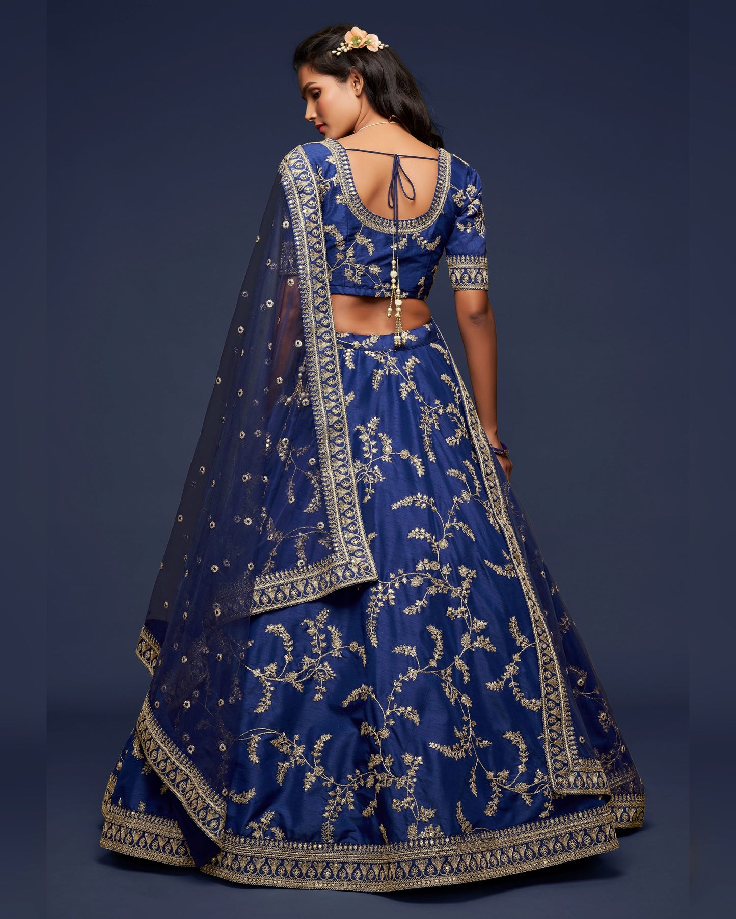 Woman wearing a blue embroidered traditional outfit against a dark background