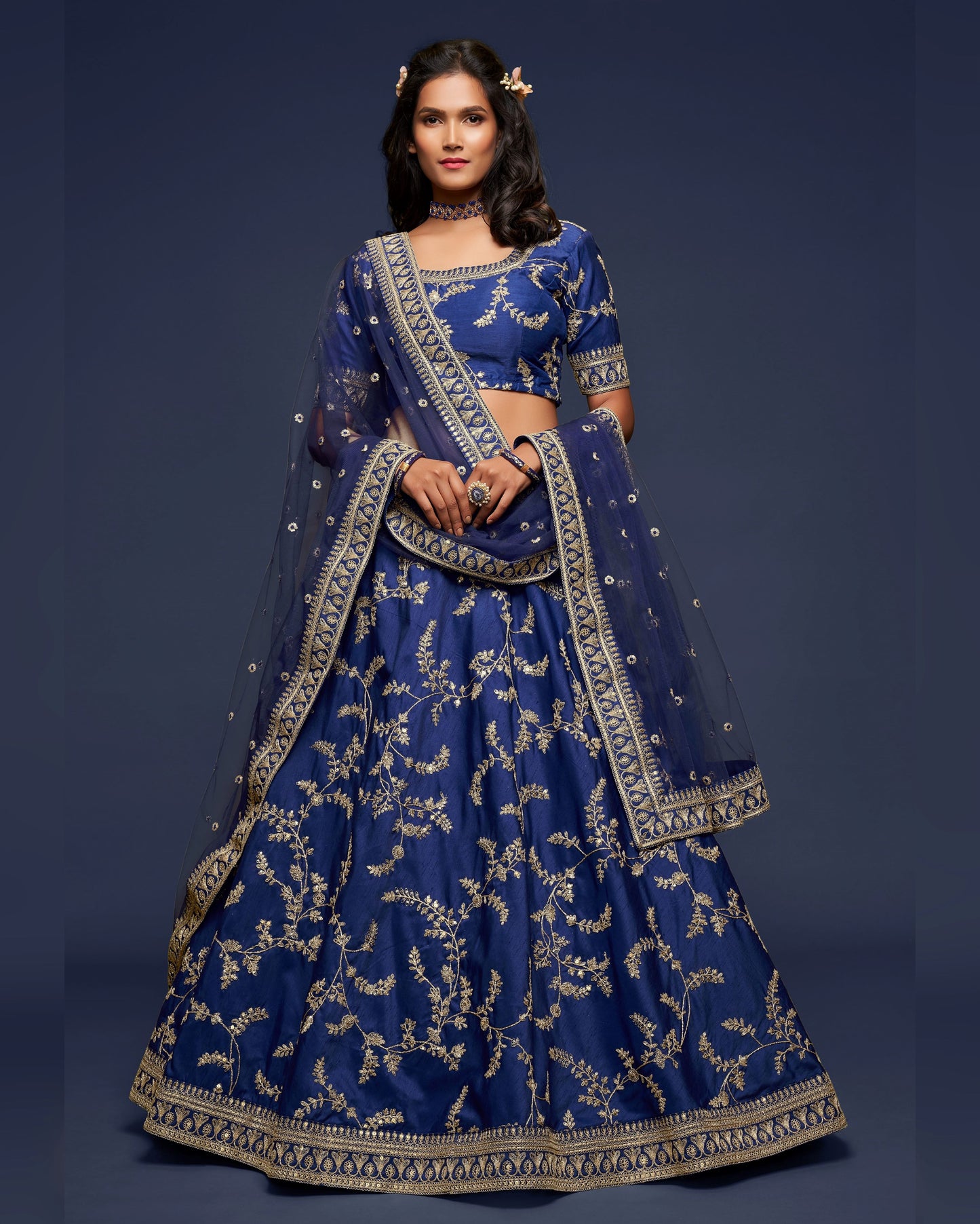 Woman wearing a traditional blue embroidered outfit against a dark background