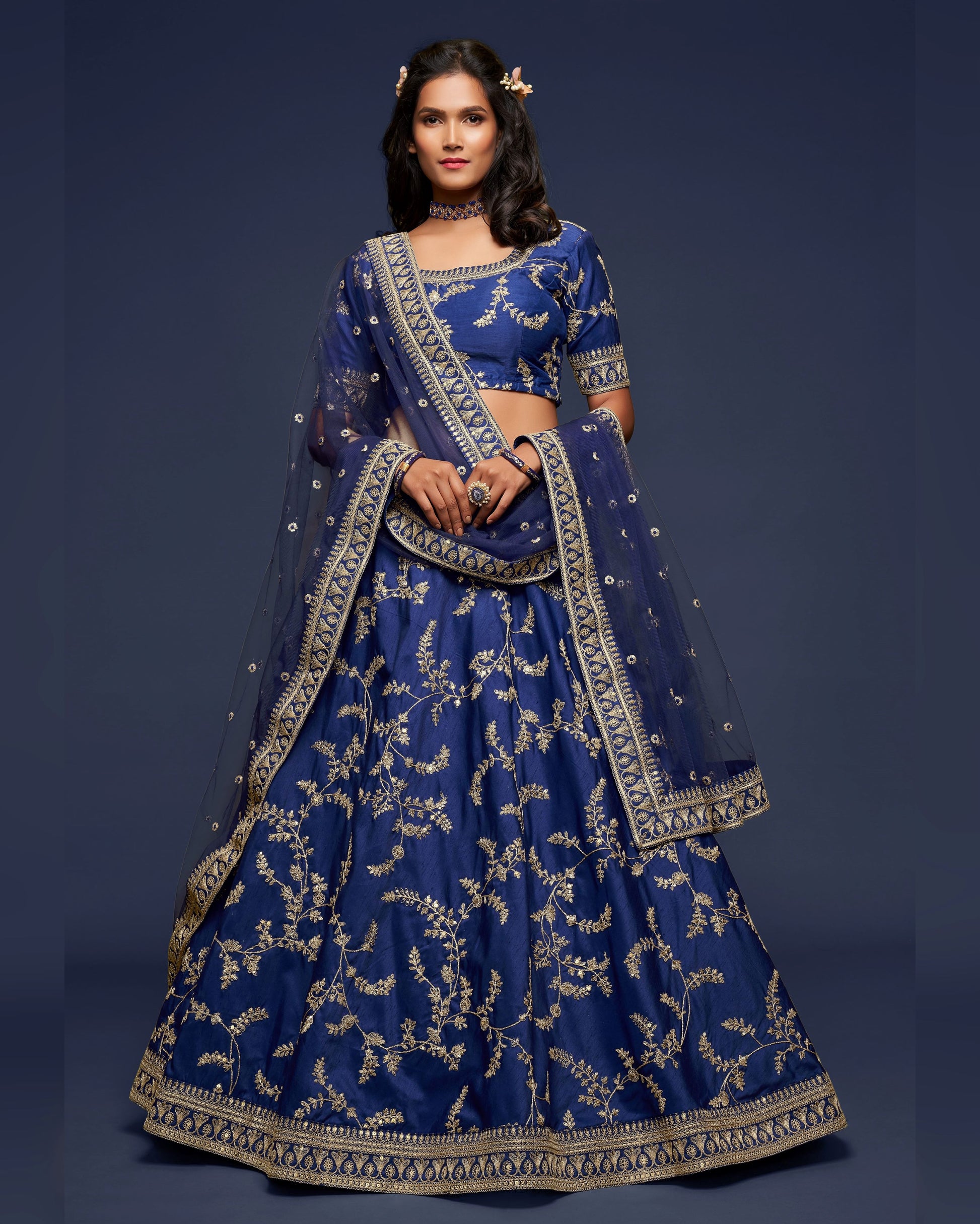 Woman wearing a traditional blue embroidered outfit against a dark background