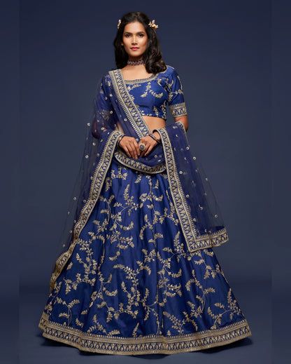 Woman wearing a traditional blue embroidered outfit against a dark background