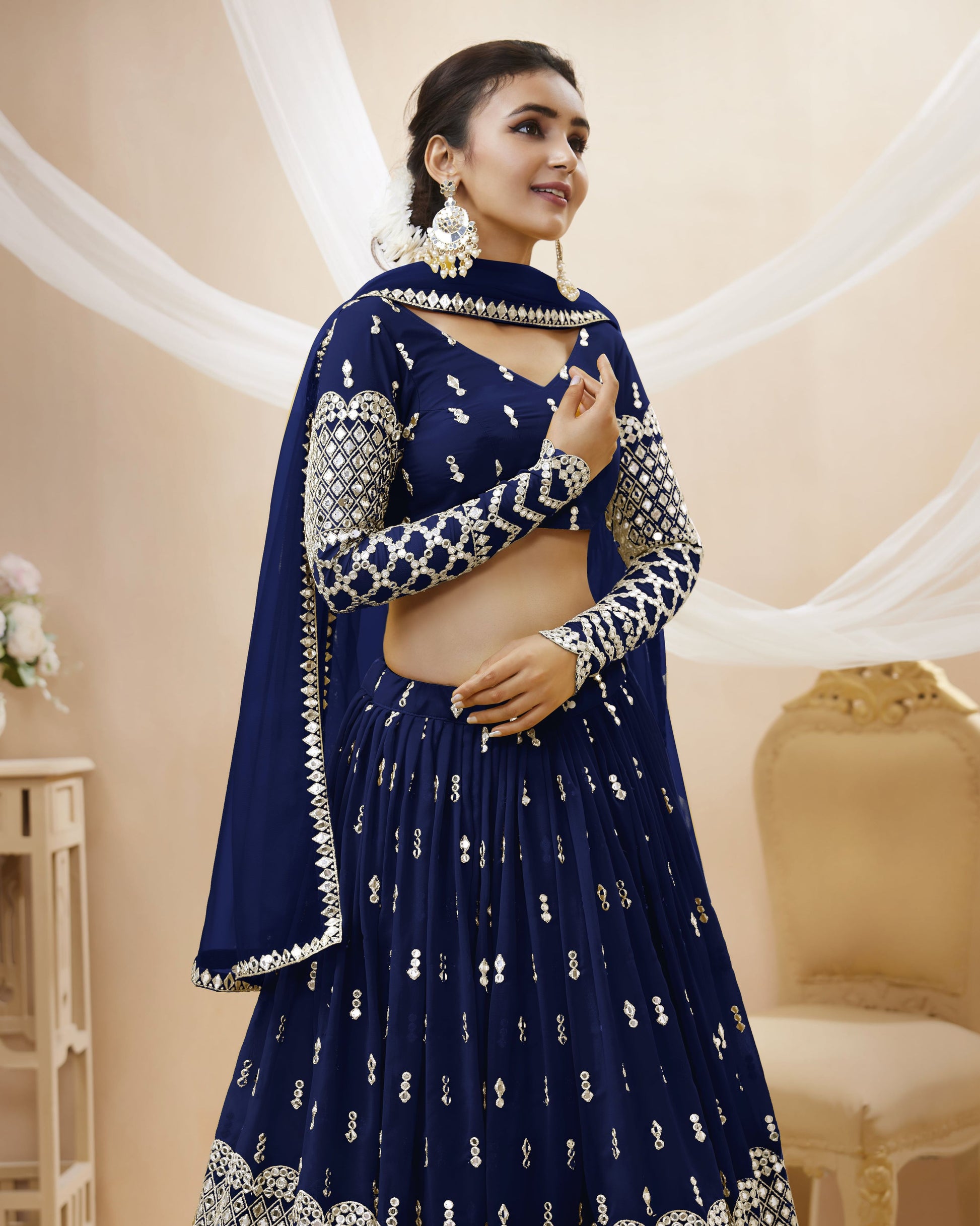 Woman wearing a navy blue embroidered traditional outfit in an elegant indoor setting.