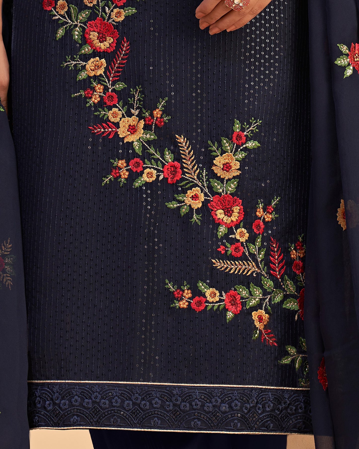 Navy blue fabric with floral embroidery in red, yellow, and green.