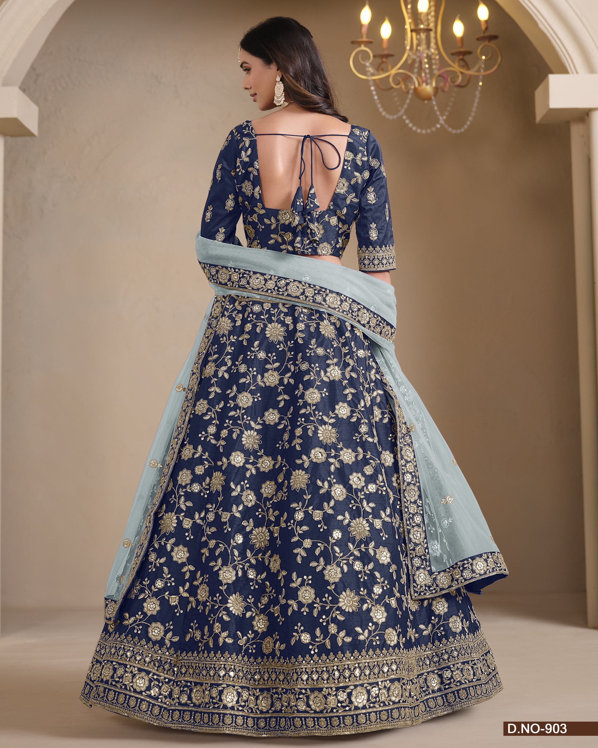Woman wearing a blue embroidered traditional outfit with a light blue dupatta in an elegant indoor setting.