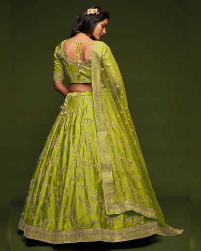 Woman wearing a green embroidered lehenga with a matching dupatta on a dark green background