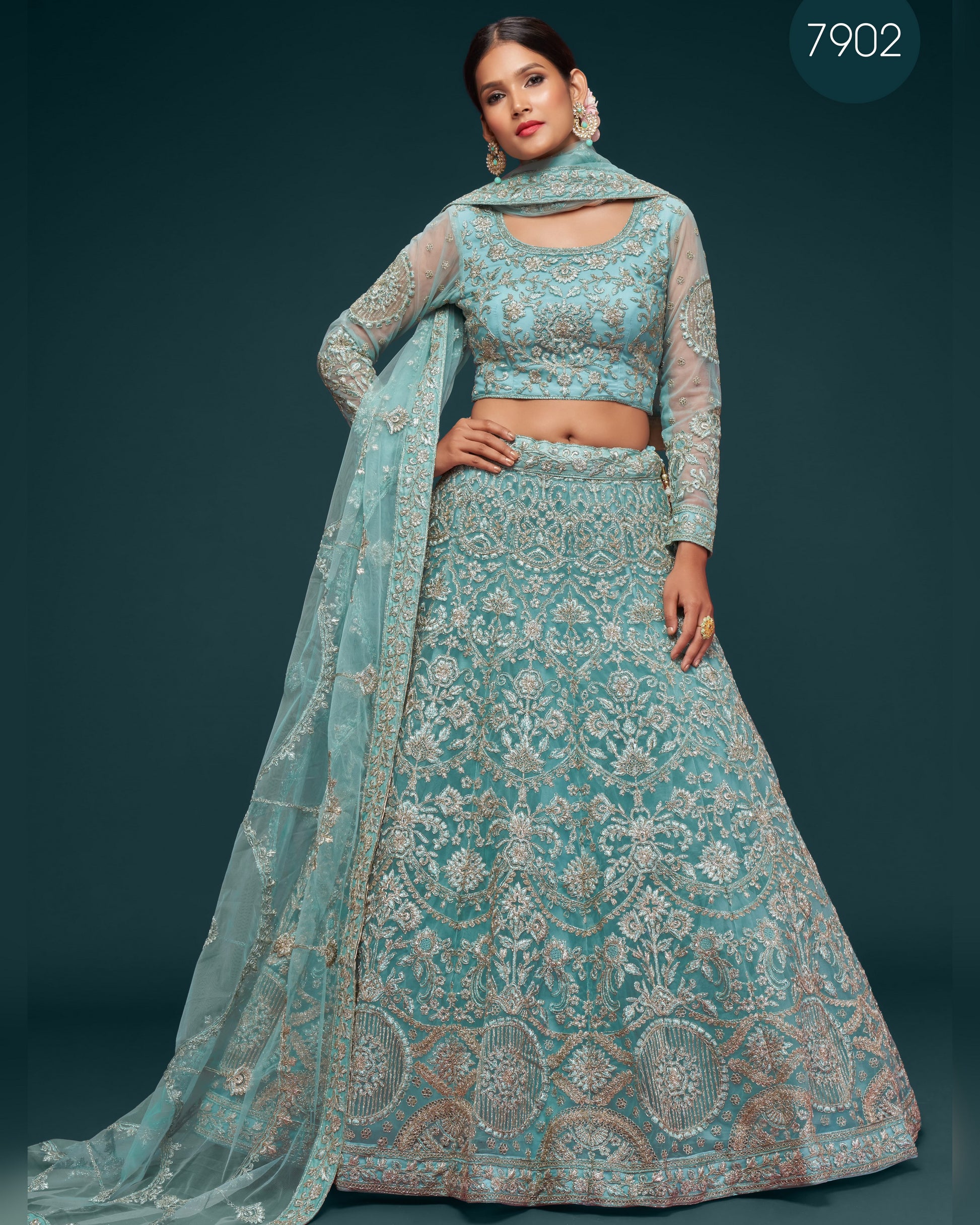 Woman wearing a teal embroidered traditional outfit with a matching dupatta on a dark background