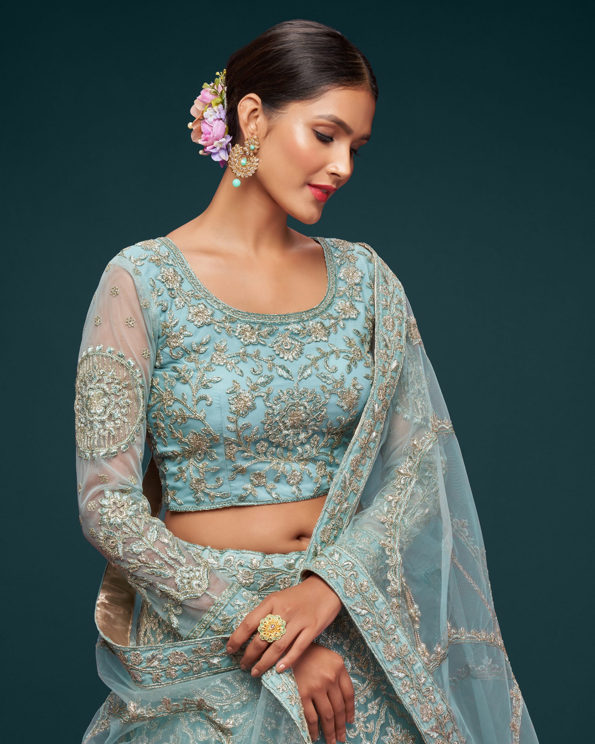 Woman wearing a light blue embroidered traditional outfit with a dark background