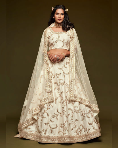 Woman wearing a traditional embroidered outfit with a sheer dupatta against a dark background