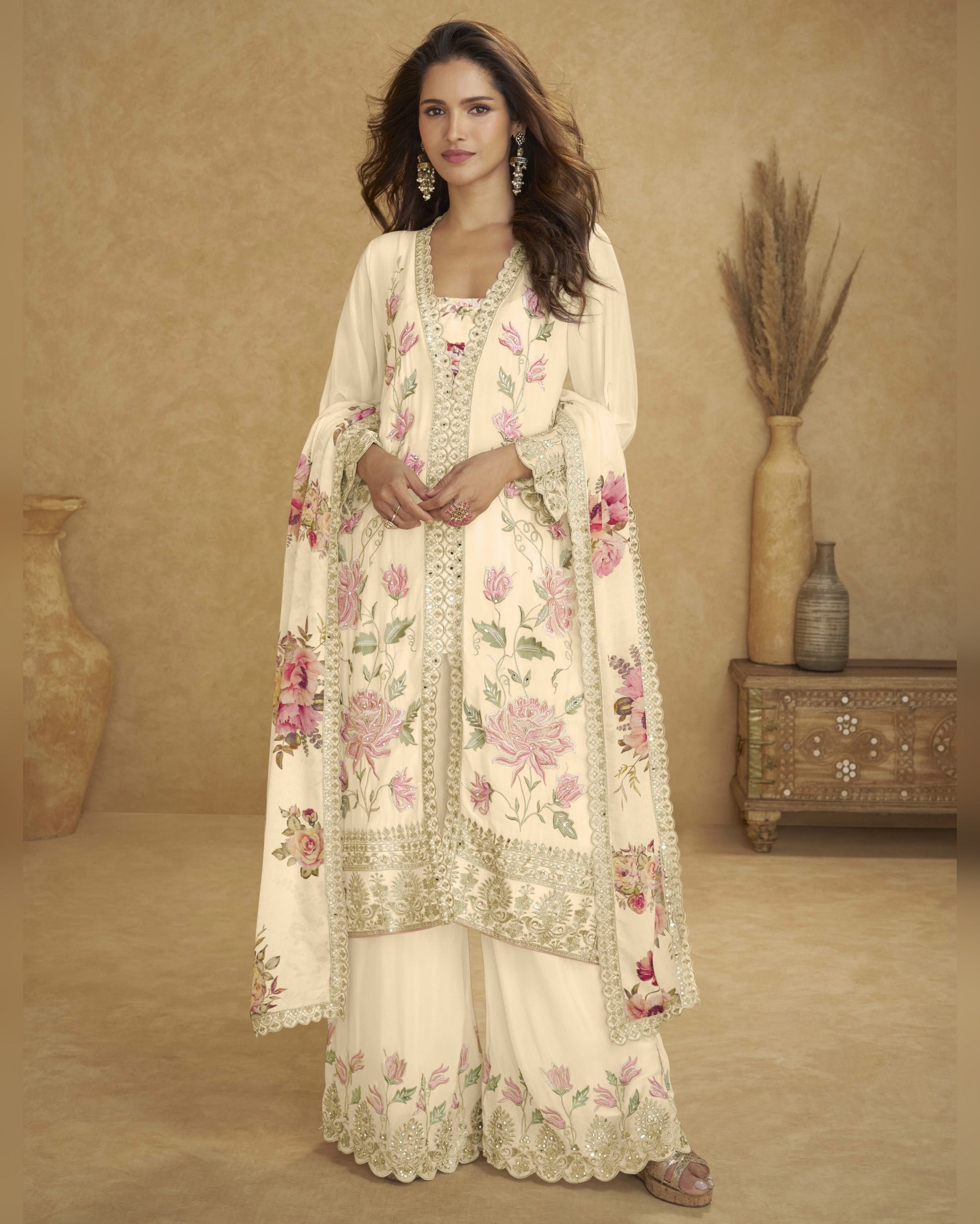Woman wearing a floral embroidered outfit in a warm-toned room.