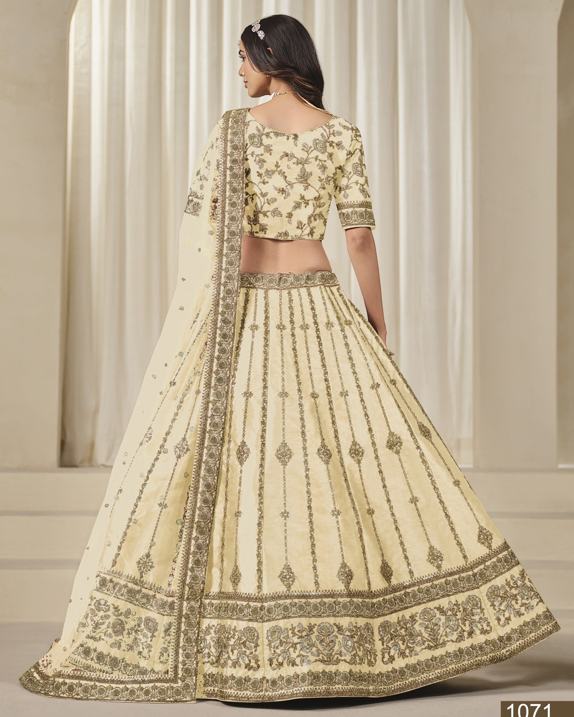 Woman wearing a cream-colored embroidered lehenga with a matching blouse in a neutral setting.