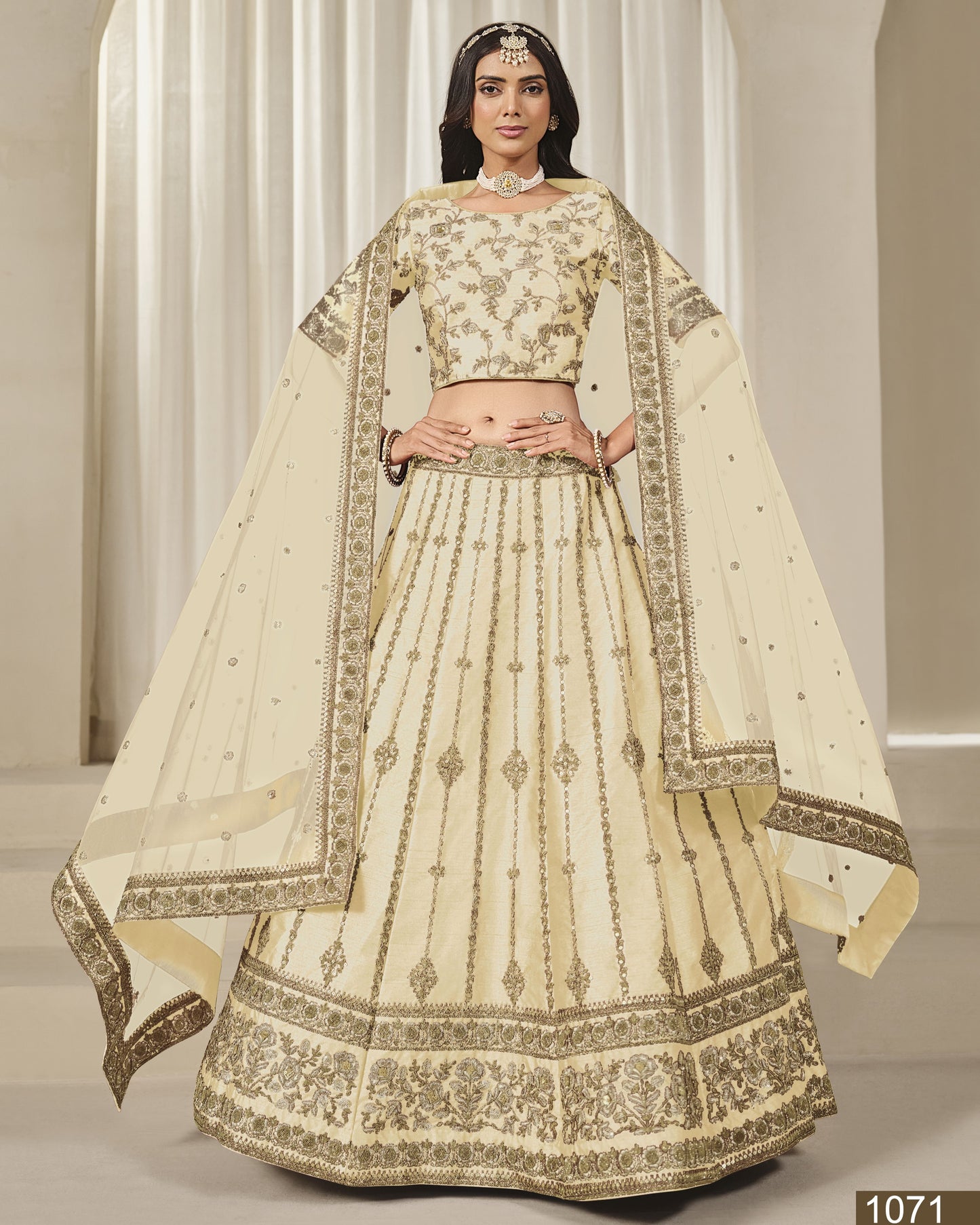 Woman wearing a traditional cream-colored embroidered lehenga with a plain background
