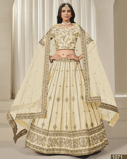Woman wearing a traditional cream-colored embroidered lehenga with a plain background