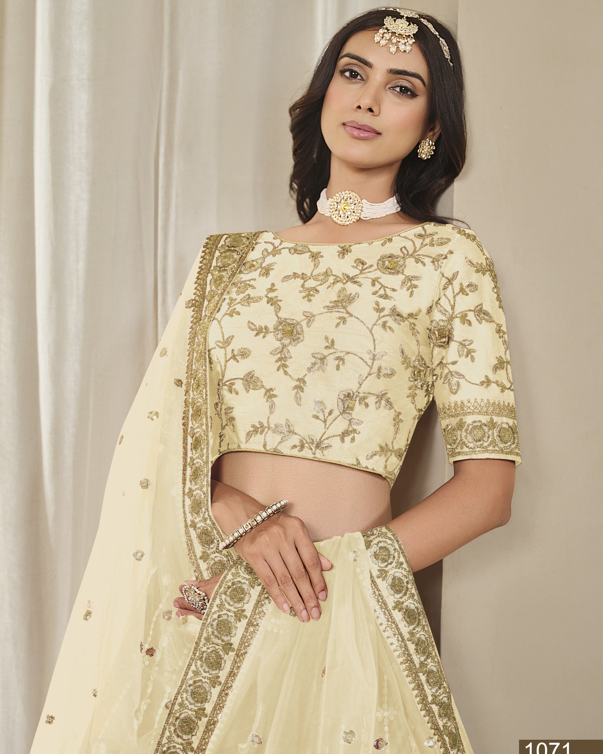 Woman wearing a cream embroidered saree with gold details against a neutral background