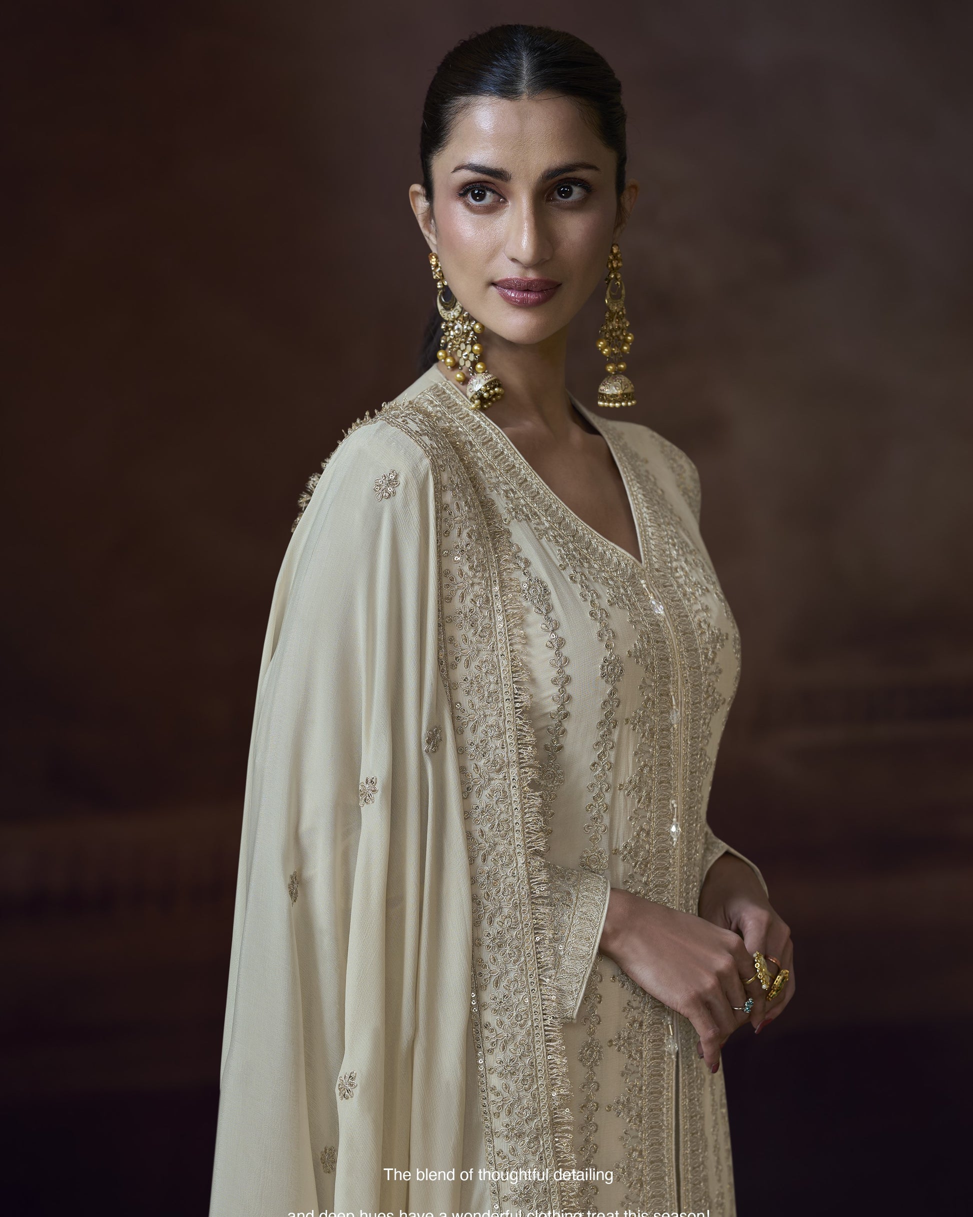 Woman wearing a traditional outfit with gold embroidery against a dark background