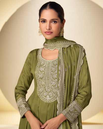 Woman wearing a green traditional outfit with intricate patterns on a beige background