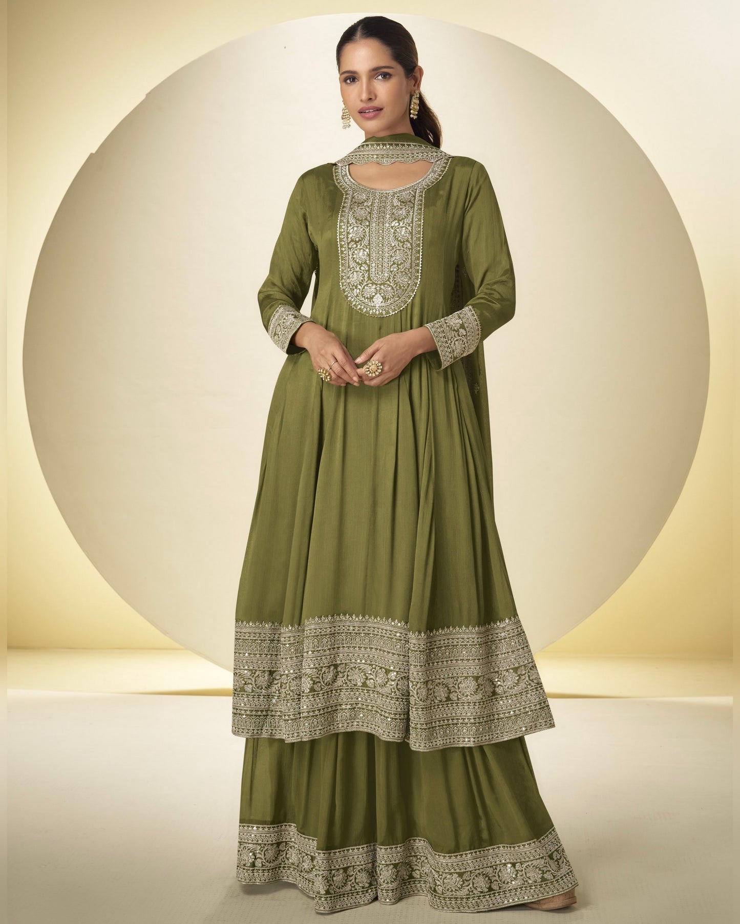 Woman wearing a green embroidered traditional outfit with a beige background