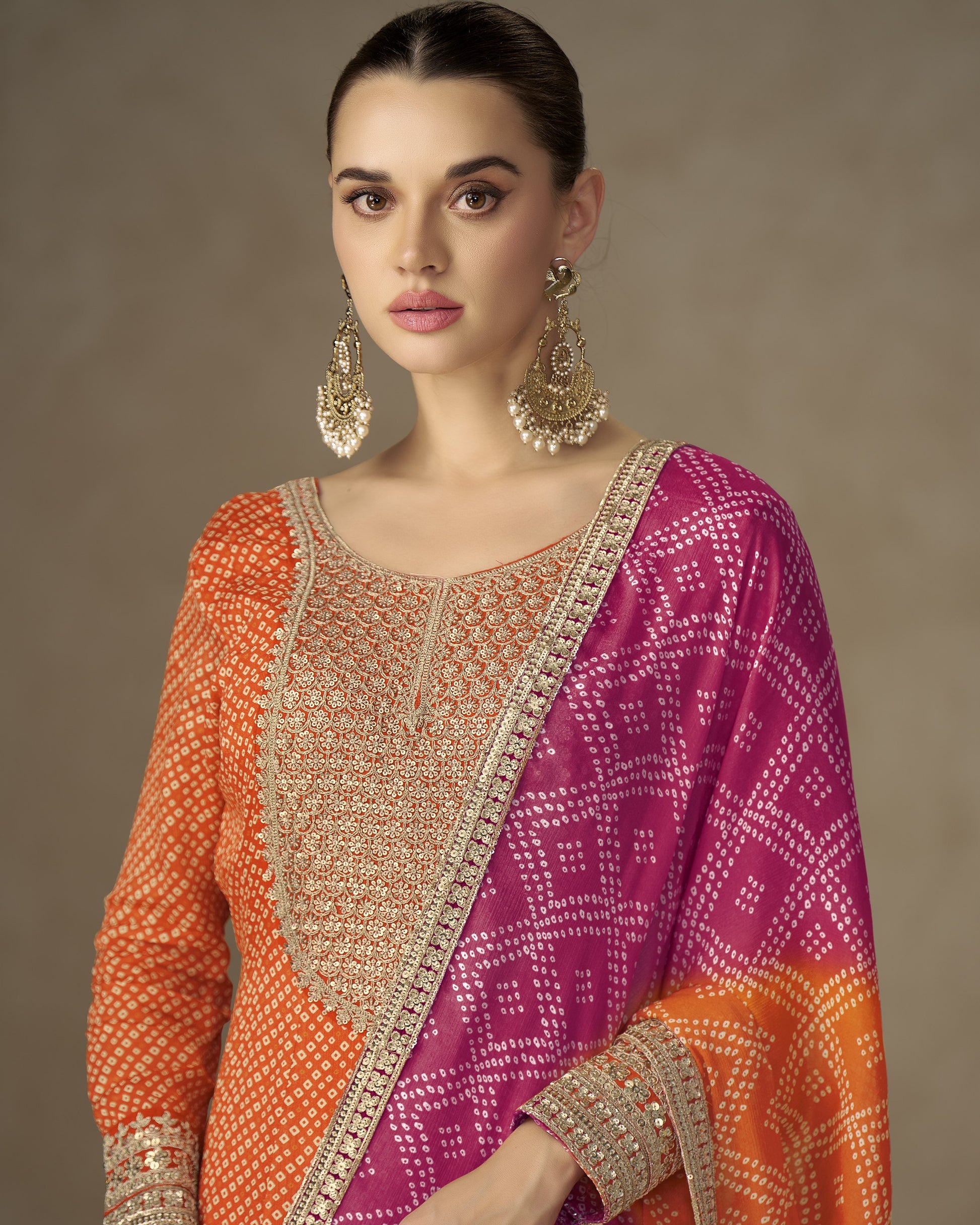 Woman wearing a traditional outfit with a pink and orange dupatta against a neutral background
