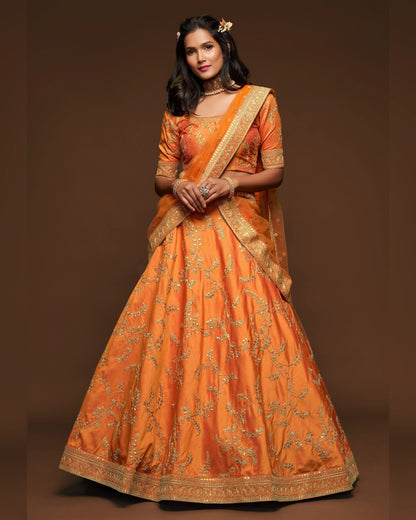 Woman wearing an orange traditional outfit with gold embroidery on a brown background