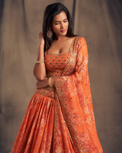Woman wearing an orange traditional outfit with intricate patterns against a neutral background