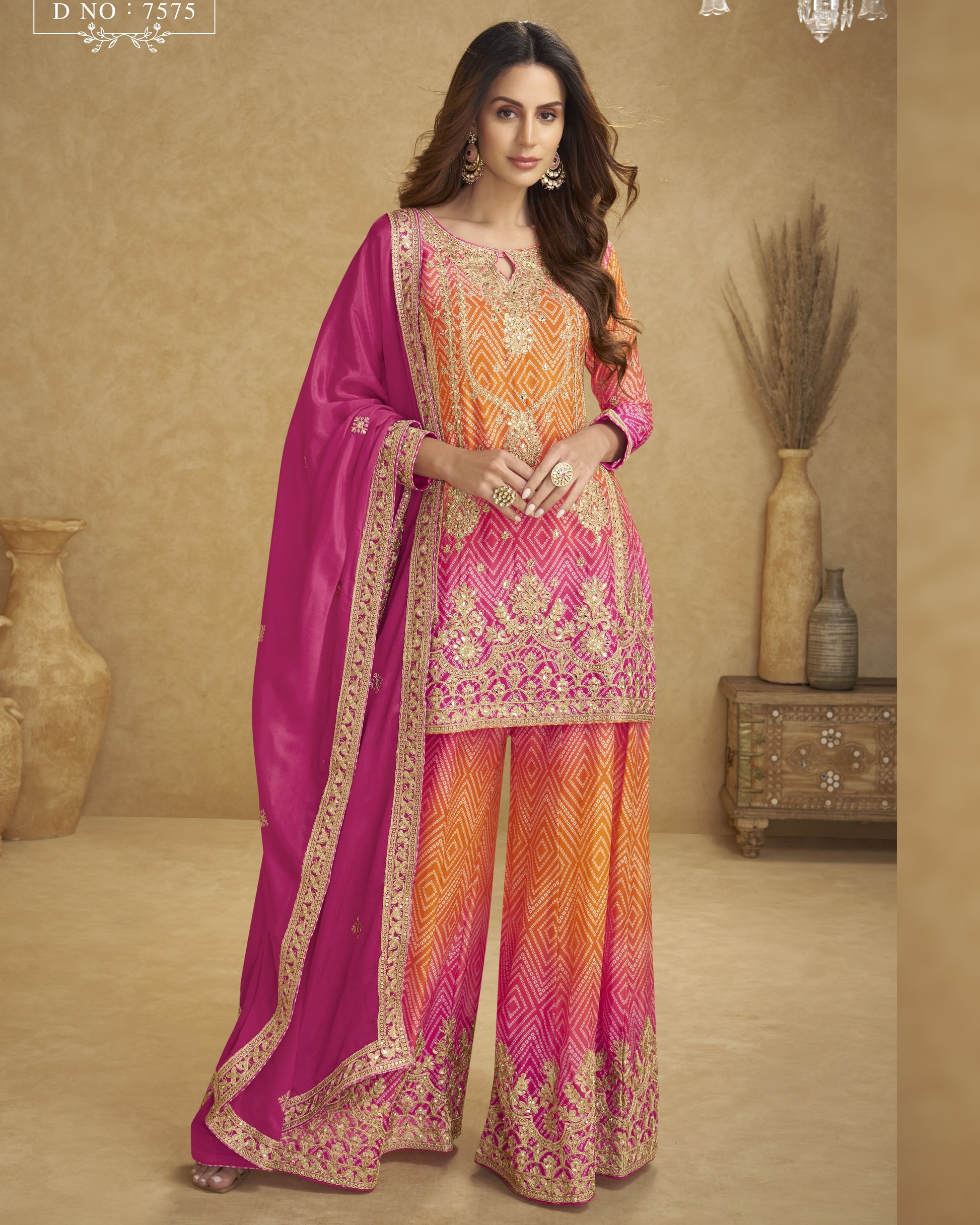 Woman wearing a traditional outfit with pink and orange patterns in a decorated room.