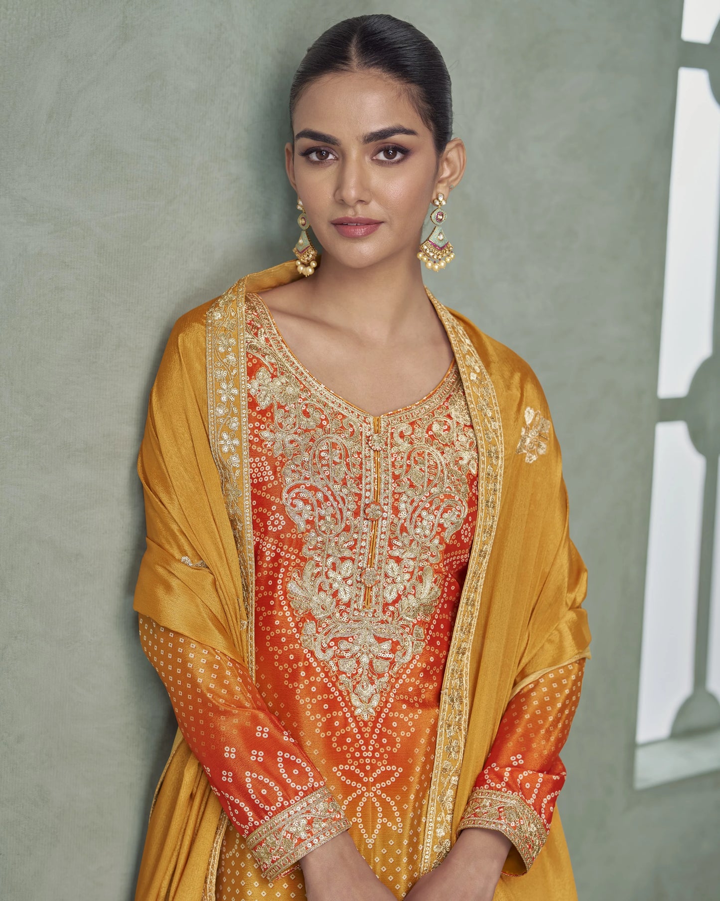 Woman wearing a traditional outfit with intricate patterns against a neutral background