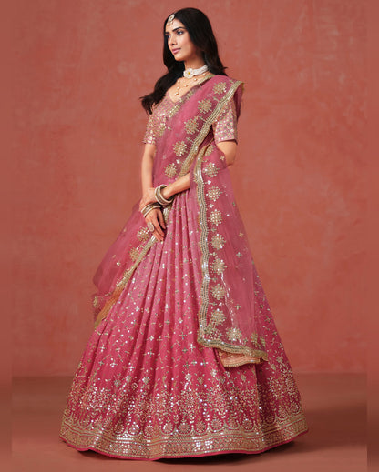 Woman wearing a pink embroidered traditional outfit against a matching background