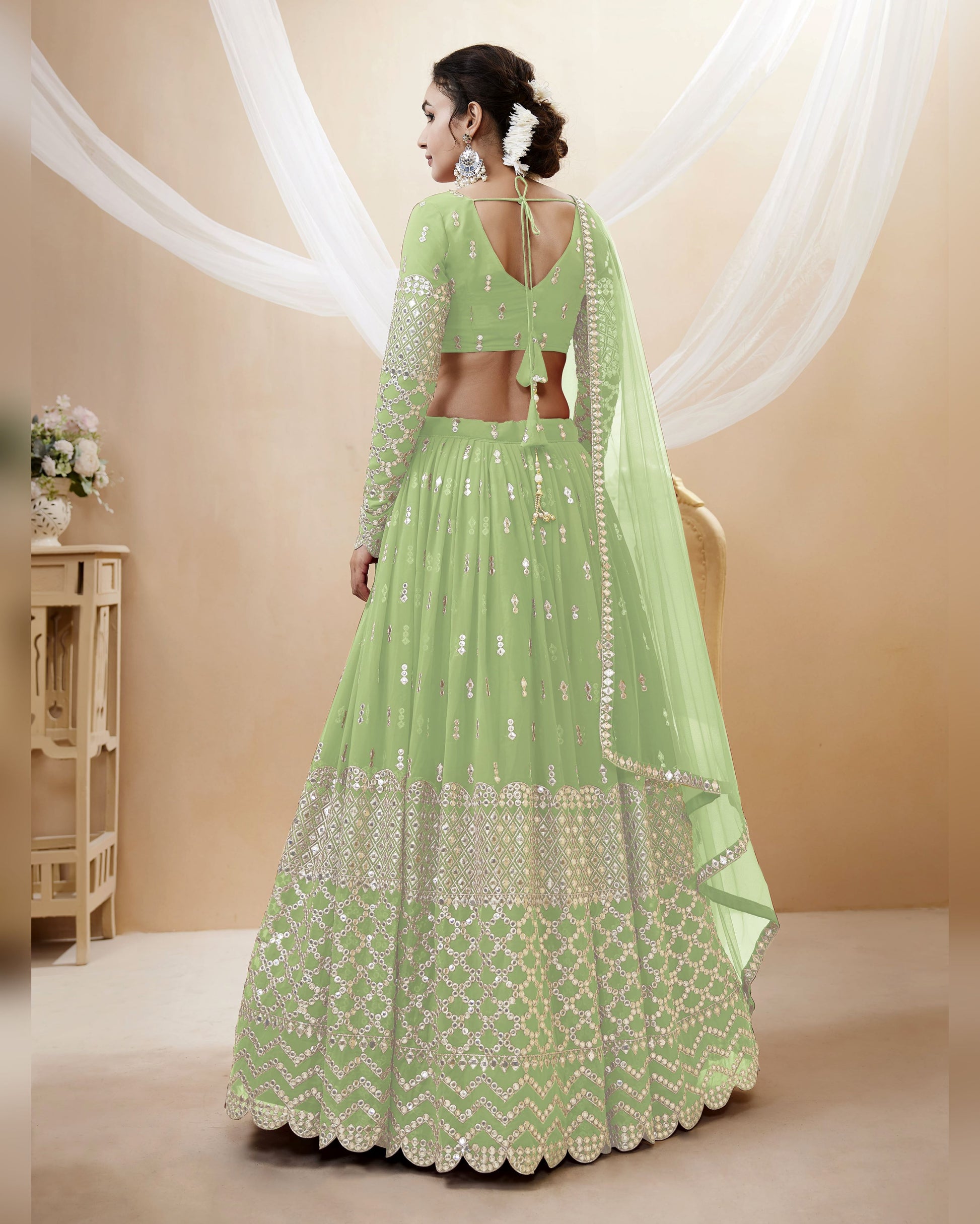 Green embroidered traditional outfit with a sheer dupatta on a beige background