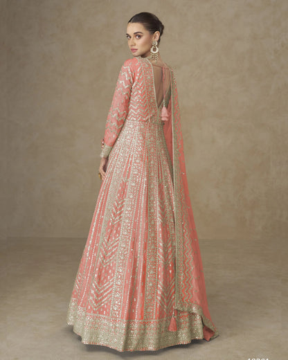 Woman wearing a traditional embroidered pink and gold dress against a beige background