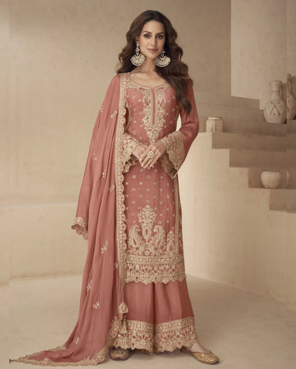 Woman wearing a traditional pink and gold embroidered outfit in a neutral setting