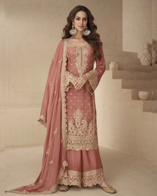 Woman wearing a traditional pink and gold embroidered outfit in a neutral setting