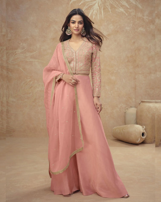 Woman in a pink traditional outfit with gold accents against a beige background