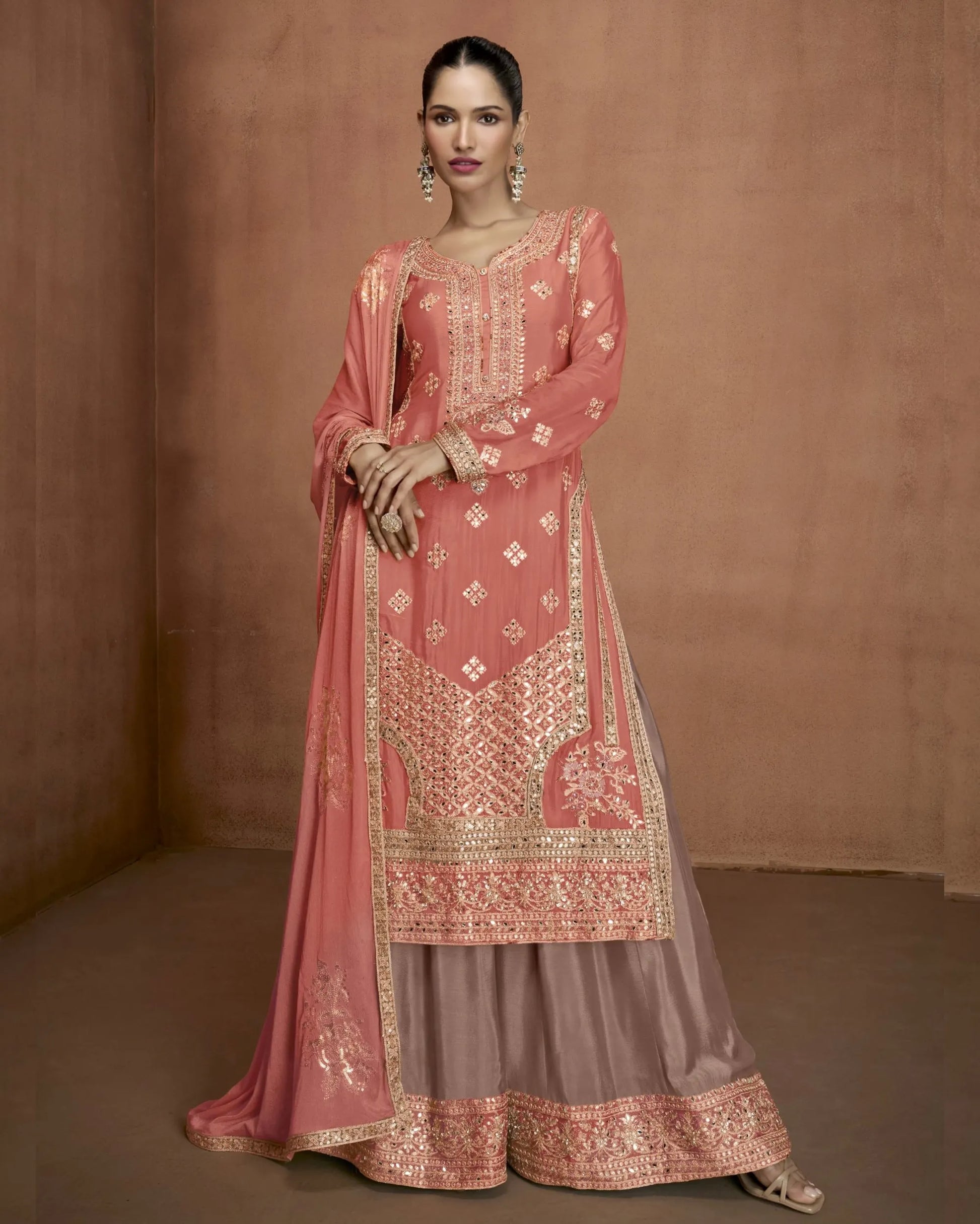 Woman wearing a traditional pink embroidered outfit against a brown background