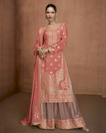 Woman wearing a traditional pink embroidered outfit against a brown background