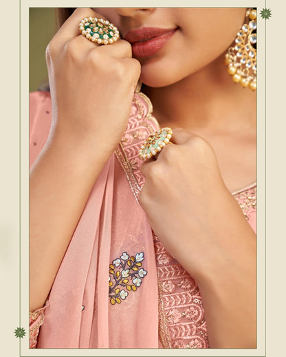 Close-up of a person wearing jewelry with a pink embroidered garment